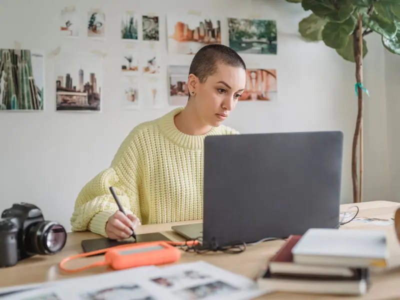 Creator drawing on a graphics tablet in front of her laptop, with a camera on the desk.