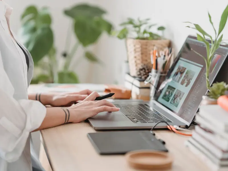 Creator editing photos on her laptop, with a tablet beside it.